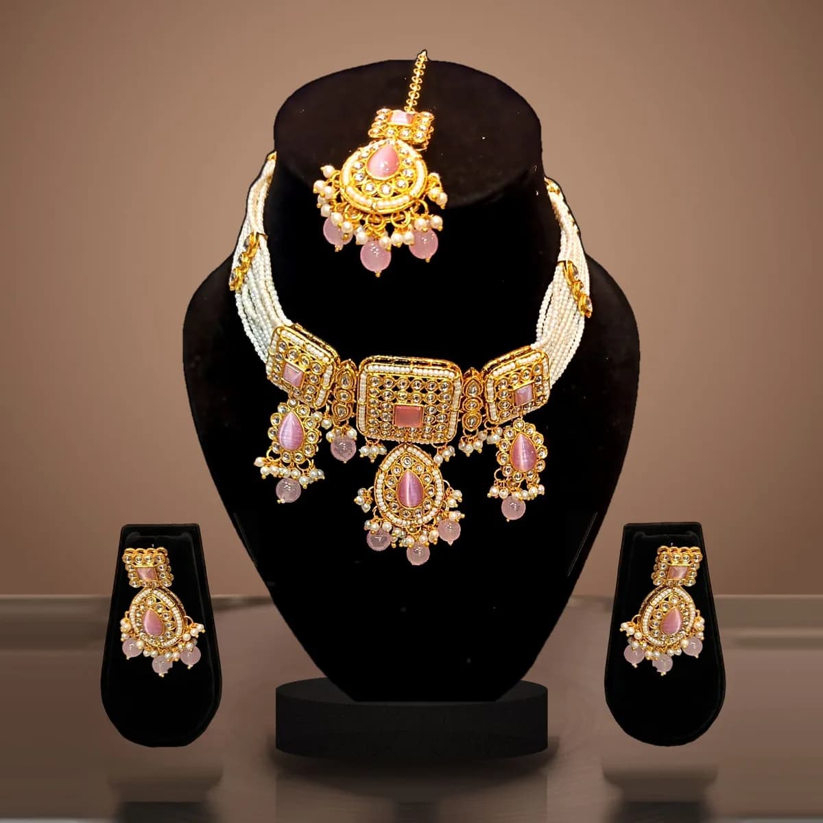 Rani Pink Kundan Pearl Choker Set with maang tikka and earrings on a velvet bust